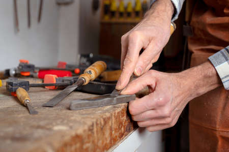 Carpenter sharpening a chisel. woodworking process with hand tools in a carpentry workshop. wood carving conceptの写真素材