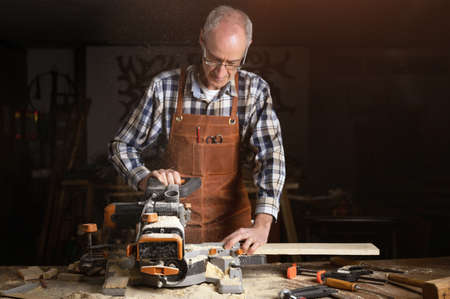 Carpenter using an electric circular saw, cutting a piece of wood.の写真素材