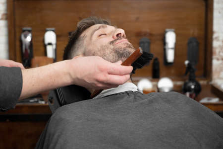 Shot of a barber using a brush on his clients beardの写真素材
