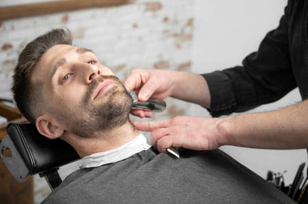 Professional barber cutting beard of handsome manの写真素材