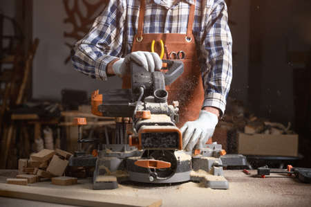 Carpenter is sawing a wood plank with electric circular saw machine in carpentry workshop. Workwood DIY conceptの写真素材