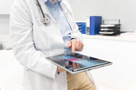 Unrecognizable Doctor is checking x-ray image at computer tablet, close up. Doctor at work in a...