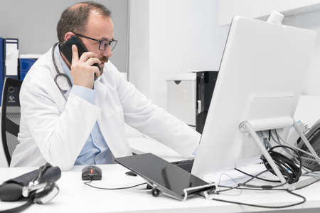 Doctor in office talking on phoneの写真素材