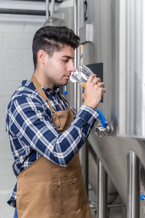 Close up view of an artisan brewer working at craft beer factory.の写真素材