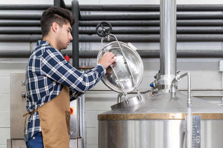 Close up view of an artisan brewer working at craft beer factory.の写真素材