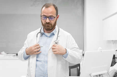 Middle age doctor man wearing white medical coat at the clinic with serious expression.の写真素材