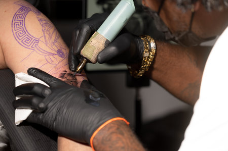Close up view of tattooing process. Master makes contouring lines with his professional tattoo machine.の写真素材