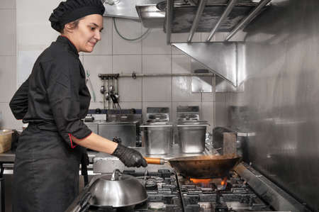 Side view of female chef working in commercial kitchenの写真素材