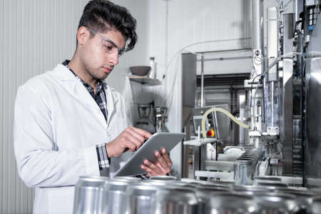 Factory worker inspecting production line on beverage factory with computer tablet.の写真素材