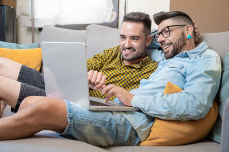 Male caucasian gay couple using laptop computer at homeの写真素材