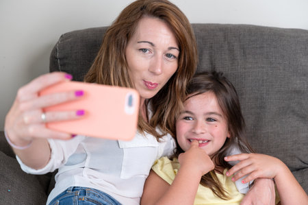 Mother and daughter taking selfie at home.の写真素材