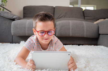 Adorable little boy using a digital tablet on the floor at home.の写真素材