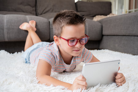 Adorable little boy using a digital tablet on the floor at home.の写真素材