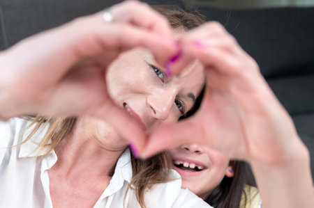 Mother and her little daughter showing heart shape with their fingers.の写真素材