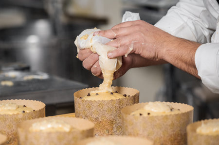 Confectioner topping panettone cakes with piping bag glazed sweet fillingの写真素材