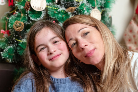 Happy mother and teenage daughter taking a selfie in front of a Christmas treeの写真素材
