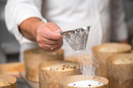 Pastry chef Topping Traditional Italian panettones with powdered sugar.の写真素材