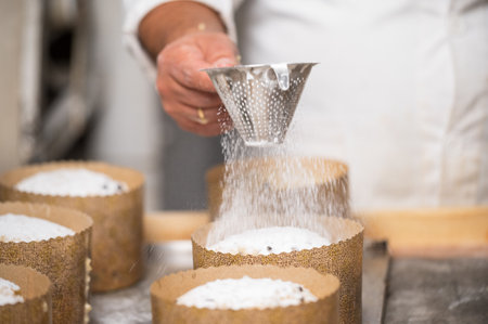 Pastry chef Topping Traditional Italian panettones with powdered sugar.の写真素材