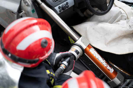 Firefighters using hydraulic tools during a rescue operation training. Rescuers unlock the passenger in car after accident.の写真素材