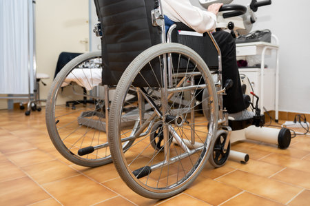 An unrecognizable elderly woman does pedal exercises from wheel chair at hospital.の写真素材
