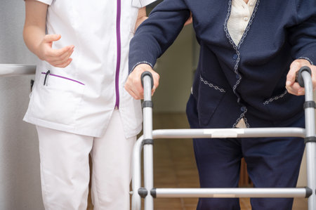 Nurse assists her senior patient on folding walker. Recuperation for elderly, seniors care, nursing home.の写真素材
