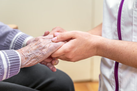 Close-up senior woman hand with her caregiver helping hands holding together, Caregiver visit at home. Home health care and nursing home concept.の写真素材