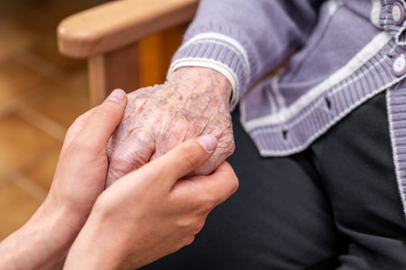 Close-up senior woman hand with her caregiver helping hands holding together, Caregiver visit at home. Home health care and nursing home concept.の写真素材