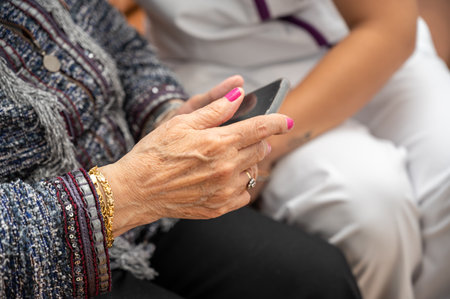 Nurse teaching elder woman how to use mobile phone, senior grandmother learning to use smartphone at...