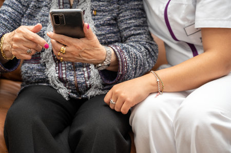 Nurse teaching elder woman how to use mobile phone, senior grandmother learning to use smartphone at nursing home. Modern technology for elderlyの写真素材