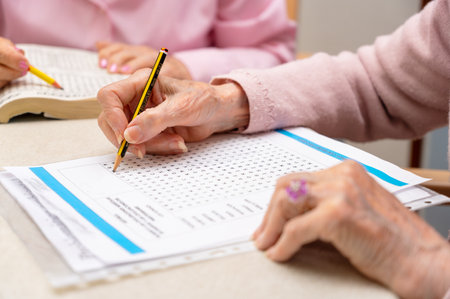 Hands of senior people solving together a word search quiz at nursing homeの写真素材