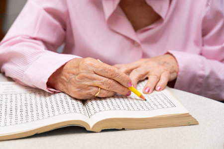 Hands of senior people solving together a word search quiz at nursing homeの写真素材