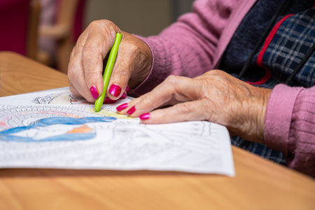 Elderly woman painting color on her drawing. Hobby at nursing home.の写真素材