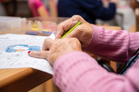 Elderly woman painting color on her drawing. Hobby at nursing home.の写真素材