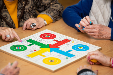 Group of unrecognizable senior woman playing the classic game Ludo or Parchis at nursing home.
