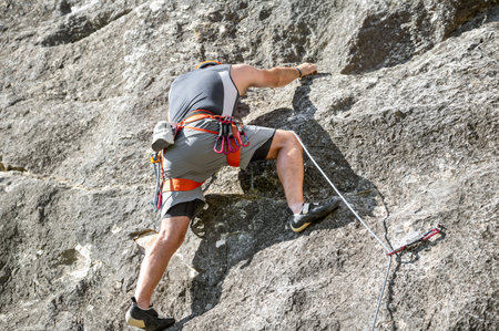 Close up of a climber with equipment on a belt, climbing a rock wallの写真素材
