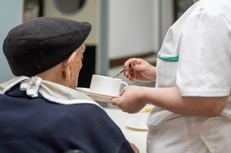 Senior man getting fed by carer in nursing home.の写真素材