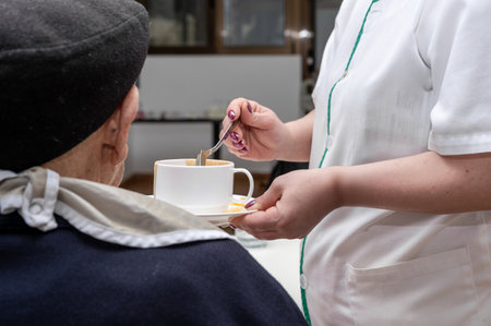 Senior man getting fed by carer in nursing home.の写真素材