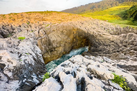 Natural sea cave at Llanes Asturias, Spain. landscape of the waves splashing at a natural rock arch.の写真素材