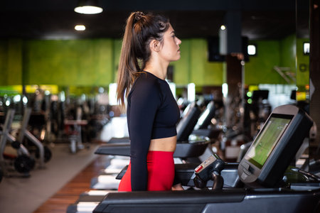 Young woman exercising and training in the gym on treadmill running machine. Healthy lifestyle and...