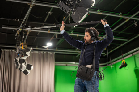 Boom microphone operator testing sound at TV studio.