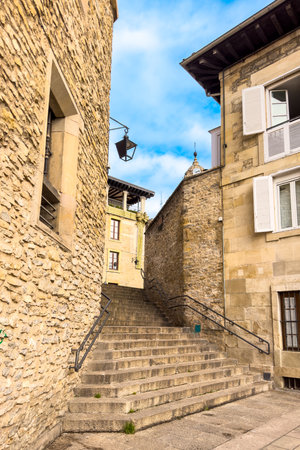 Historic street in Vitoria-Gasteiz old town with traditional Basque architecture, stone buildings and a clock tower under a blue sky, Spain.の写真素材