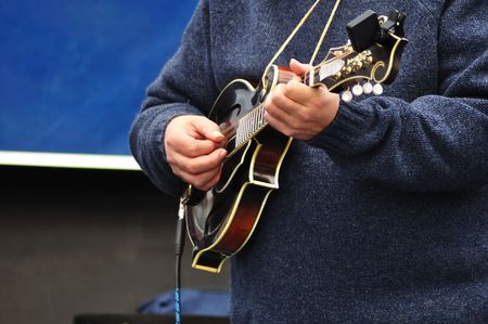 Man Wearing Blue Sweater Strumming a Mandolin の写真素材