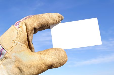 Worker Wearing Leather Work Glove Holding a Blank Business Card Against a Blue Skyの写真素材