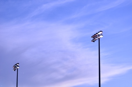 Brightly Lit Stadium Lights Against the Evening Skyの写真素材