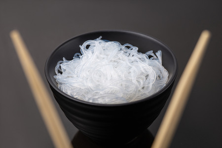 Rise noodles in black bowl on wooden backgroundの写真素材
