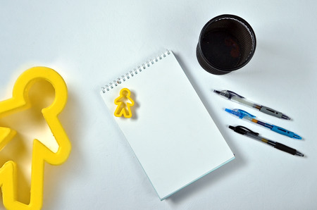 text on notepad with office accessories. Business motivation, inspiration concepts using blue pen or black pens behind case and yellow person toy on white paper backgroundの写真素材