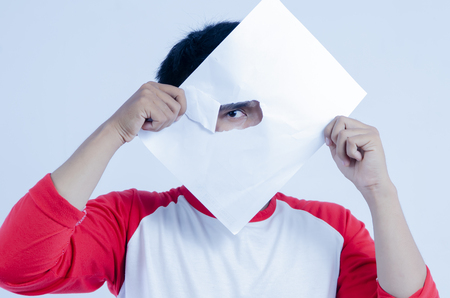 Men's eye peeking through a paper hole on white backgroundの写真素材