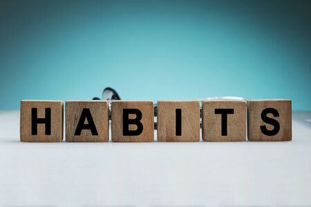 What is your habits? Sign with the word habits on white desk in a blue backgroud