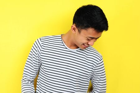 Portrait confident happy young Asian man Human emotion, isolated on yellow backgroundの写真素材