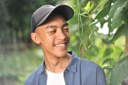 Happy of young Asian farmer male looking at the long beans, on the garden.